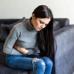 sick_woman_having_stomachache_living_room_1_10b3afb81b